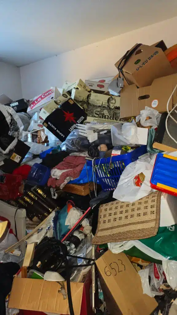Pokój zapełniony po sufit kartonami, odzieżą i przedmiotami w mieszkaniu zbieracza